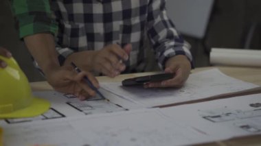 Team of 2 professional engineers in vests and helmets brainstorming plans in building and house construction project in 4k conference room.