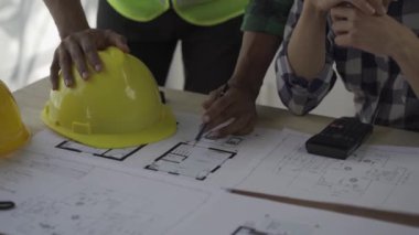 Team of 2 professional engineers in vests and helmets brainstorming plans in building and house construction project in 4k conference room.