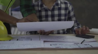 Team of 2 professional engineers in vests and helmets brainstorming plans in building and house construction project in 4k conference room.