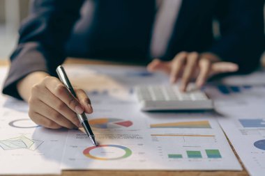 Hand of a business man using a calculator to check financial accounts, check expenditures and company budget. Female accountant calculating while working analyzing business reports at work