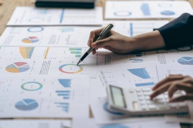 Hand of a business man using a calculator to check financial accounts, check expenditures and company budget. Female accountant calculating while working analyzing business reports at work