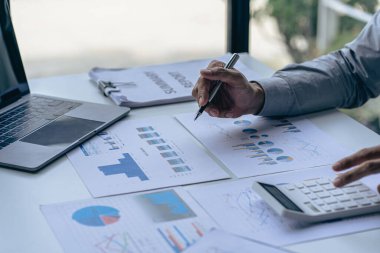 Hand of a business man using a calculator to check financial accounts, check expenditures and company budget. Female accountant calculating while working analyzing business reports at work