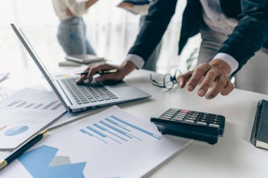 Hand of a business man using a calculator to check financial accounts, check expenditures and company budget. Female accountant calculating while working analyzing business reports at work