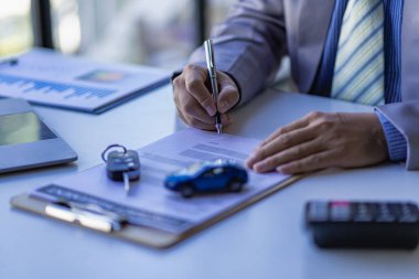 A car dealer or sales manager offers to sell a car and explains the terms of signing a car and insurance contract.