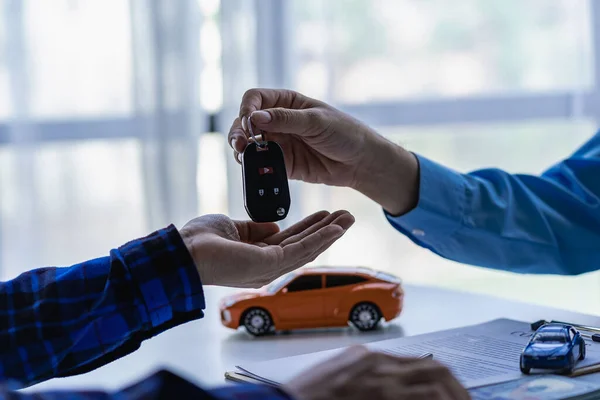 A car dealer or sales manager offers to sell a car and explains the terms of signing a car and insurance contract.