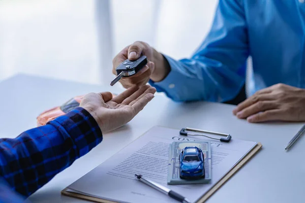 A car dealer or sales manager offers to sell a car and explains the terms of signing a car and insurance contract.