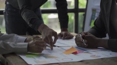 Business meeting of various multinational conglomerates They discuss and analyze the success of work in their company. Examine the graph chart on the table in the office 4K