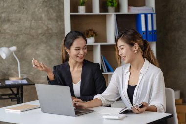 Two beautiful and attractive Asian businesswoman or female accountants work together in the office. teamwork concept Work on sales and financial reports.