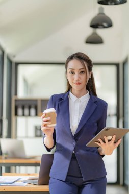 Asian businesswoman working with various electronic internet devices, independent woman having tablet and laptop with chart, multitasking theme, financial accounting concept. vertical image