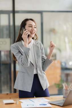 Asian businesswoman working with various electronic internet devices, independent woman having tablet and laptop with chart, multitasking theme, financial accounting concept. vertical image