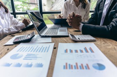 Group of businessmen holding smart pen discussing in group meeting at table in modern office with graph papers and laptop Strategic Planning, Business Collaboration and Brainstorming of Colleagues