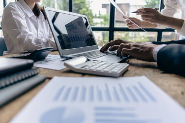 Group of businessmen holding smart pen discussing in group meeting at table in modern office with graph papers and laptop Strategic Planning, Business Collaboration and Brainstorming of Colleagues