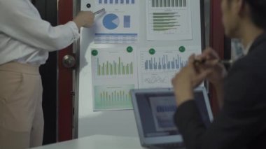 Group of Asian businessmen brainstorming close-up at plan meeting statistical analysis and pointing graph employee taking notes with laptop on table finance business success statistics concept