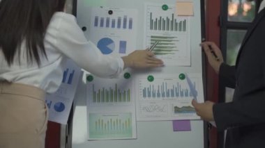 Group of Asian businessmen brainstorming close-up at plan meeting statistical analysis and pointing graph employee taking notes with laptop on table finance business success statistics concept