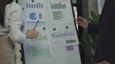 Group of Asian businessmen brainstorming close-up at plan meeting statistical analysis and pointing graph employee taking notes with laptop on table finance business success statistics concept