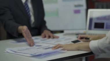 Group of Asian businessmen brainstorming close-up at plan meeting statistical analysis and pointing graph employee taking notes with laptop on table finance business success statistics concept