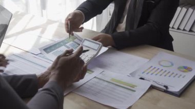 Group of Asian businessmen brainstorming close-up at plan meeting statistical analysis and pointing graph employee taking notes with laptop on table finance business success statistics concept