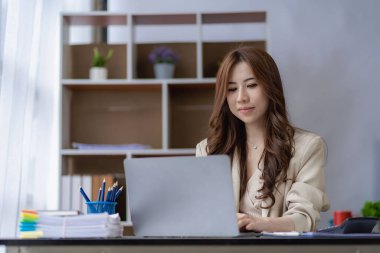 Asian businesswoman working with financial documents and laptop Inside office worker calculating financial indicators smiling and happy with success and results of business success