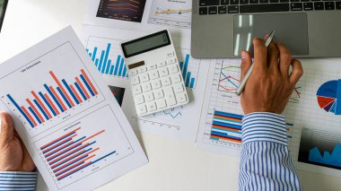 Businessman or accountant holding pen working on business financial data, accounting documents and laptop calculator at office, business concept. Top view