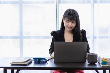 Busy businesswoman working on laptop computer at office Working on financial accounting report in office, friendly smiling woman in front desk typing on computer