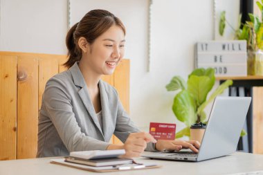 Asian woman holding credit card and typing keyboard on laptop online shopping Girl doing online checkout using laptop for shopping at home online shopping concept