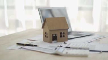 Bank officer or businessman working with documents and house model with laptop on table, real estate business concept 4k