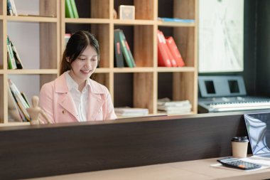 Young black-haired asian female worker working in office with financial documents and laptop calculating company annual budget accounting.