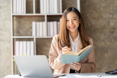 Asyalı bir bayan çalışanın elinde bir defter var. Yeni açılan bir şirketin pazarlama bölümünde çalışıyor. Müşterilerle irtibat kurmak ve tavsiye vermek için para aldı. pazarlama kavramı