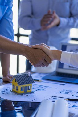 Successful collaboration concept, architect and construction engineer holding hands while working for teamwork and cooperation after completion of agreement in office