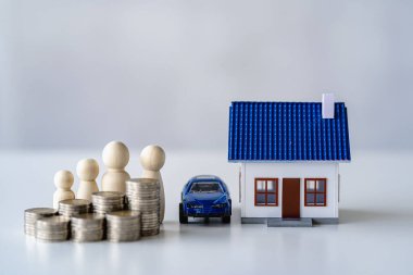 The house and the car are behind a pile of wooden puppet coins. Real estate investment. Home mortgage. Savings finance concept, full property insurance.