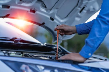 Young man checking and maintaining the quality of engine oil in his car Car repair and maintenance, oil change before long journey, car mechanic concept