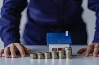 Stack of coins and growing businessman hand house or house model. Business. Investment. Retirement Planning. Finance and insurance concept