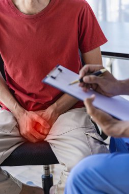 A doctor is consulting with a young man about prostate cancer and venereal disease and sexual dysfunction about the causes of erectile dysfunction in the exam room.