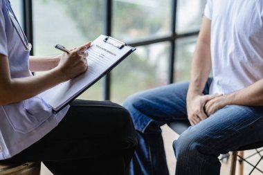 A doctor is consulting with a young man about prostate cancer and venereal disease and sexual dysfunction about the causes of erectile dysfunction in the exam room.