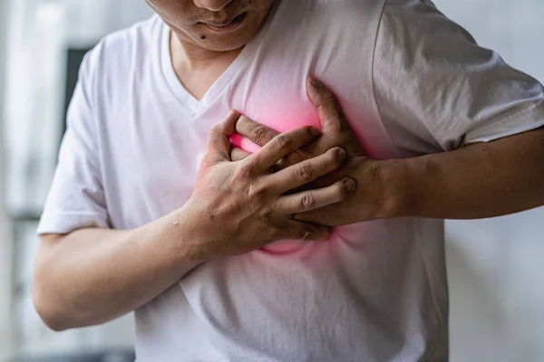 Young Asian man having chest pain, heart disease, chest pain, heart attack symptoms, man suffering from sadness on gray background, health concept