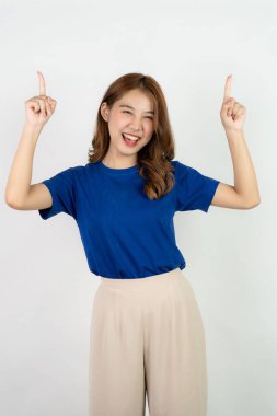 Asian woman in blue shirt standing on white background making hand gesture