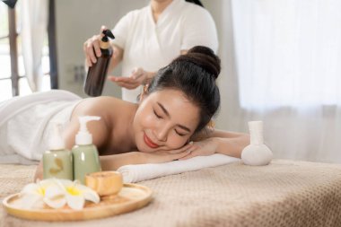 beautiful woman in spa environment Asian woman in bathrobe on sofa as she spas herself with massages and facials at home. concept of beauty