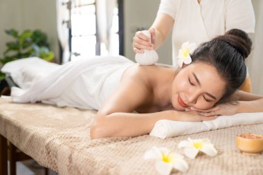 beautiful woman in spa environment Asian woman in bathrobe on sofa as she spas herself with massages and facials at home. concept of beauty