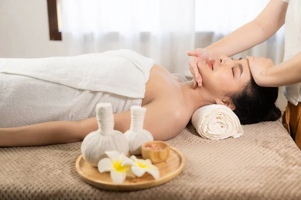 beautiful woman in spa environment Asian woman in bathrobe on sofa as she spas herself with massages and facials at home. concept of beauty