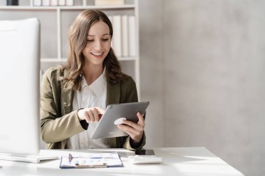 Confident smiling businesswoman using tablet working on financial statistics presentation with graph document, female accountant analyzing data in office