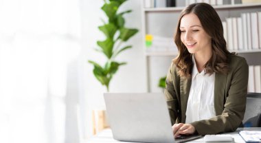 American businesswoman smiling confidently using laptop computer working on financial statistics presentation with graph document Female accountant analyzing data in office looking at camera