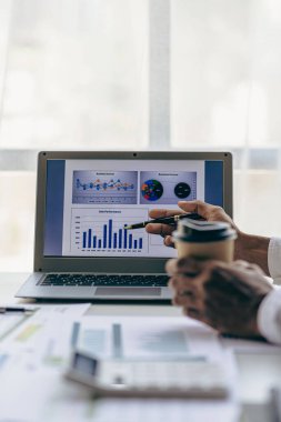 Businessmen meeting using laptop computers calculator stock market chart paper for analysis Quality improvement plan in business idea discussion meeting vertical image