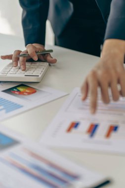 Businessmen meeting using laptop computers calculator stock market chart paper for analysis Quality improvement plan in business idea discussion meeting vertical image