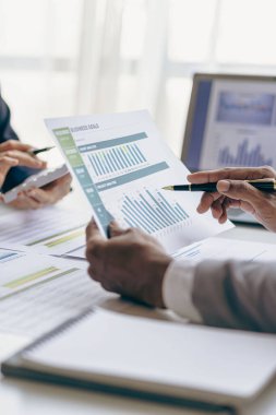 Businessmen meeting using laptop computers calculator stock market chart paper for analysis Quality improvement plan in business idea discussion meeting vertical image