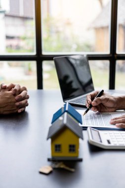 Real estate agents offer contracts and interest rates to buy or rent a residence. and businessman in front of house model, small building concept property and real estate insurance vertical image