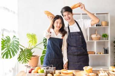 Beautiful young couple preparing breakfast together in modern kitchen Kitchen man preparing food with bread and fruit in cozy kitchen in cozy house.