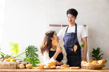 Beautiful young couple preparing breakfast together in modern kitchen Kitchen man preparing food with bread and fruit in cozy kitchen in cozy house.