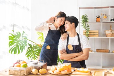 Beautiful young couple preparing breakfast together in modern kitchen Kitchen man preparing food with bread and fruit in cozy kitchen in cozy house.