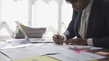 Finansal danışman listeleri okur, hesaplar, mali grafikleri analiz eder ve çalışan müşterileri belgelemek için ofiste tek başına çalışırken notlar alır. finansal muhasebe kavramları