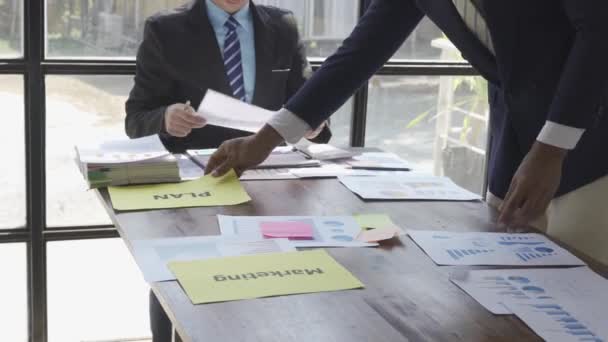 紙のプロジェクトをグラフやチャートで議論するスーツの2人のビジネスマン ダークオフィスにおける財務資料のポイント — ストック動画